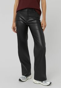 Pantalons en cuir noir synthétique avec une coupe droite, dotés d'une fermeture éclair à l'avant, de passants de ceinture et d'une texture lisse.