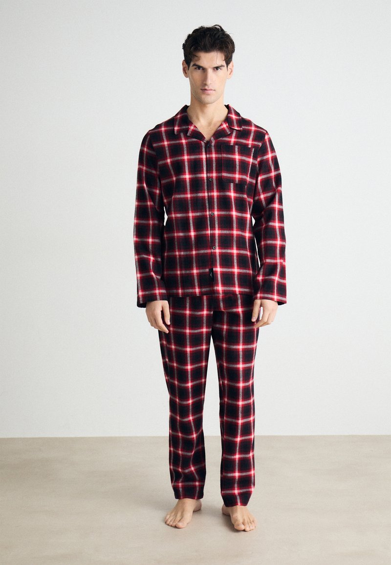 Röd och svart rutig flanellpyjamas med en knäppning skjorta med ficka och matchande byxor med elastisk midja.