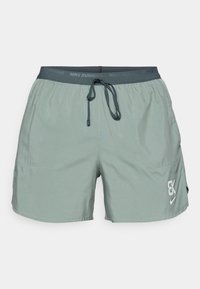 Pantalones cortos de running Nike de color verde claro con cinturilla elástica, cordón ajustable, dos bolsillos laterales y un logo en la parte inferior de la pierna derecha.