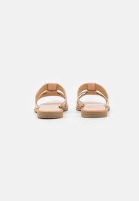Nude leather sandals with an open back, featuring two straps and a flat sole with a textured tread for grip.