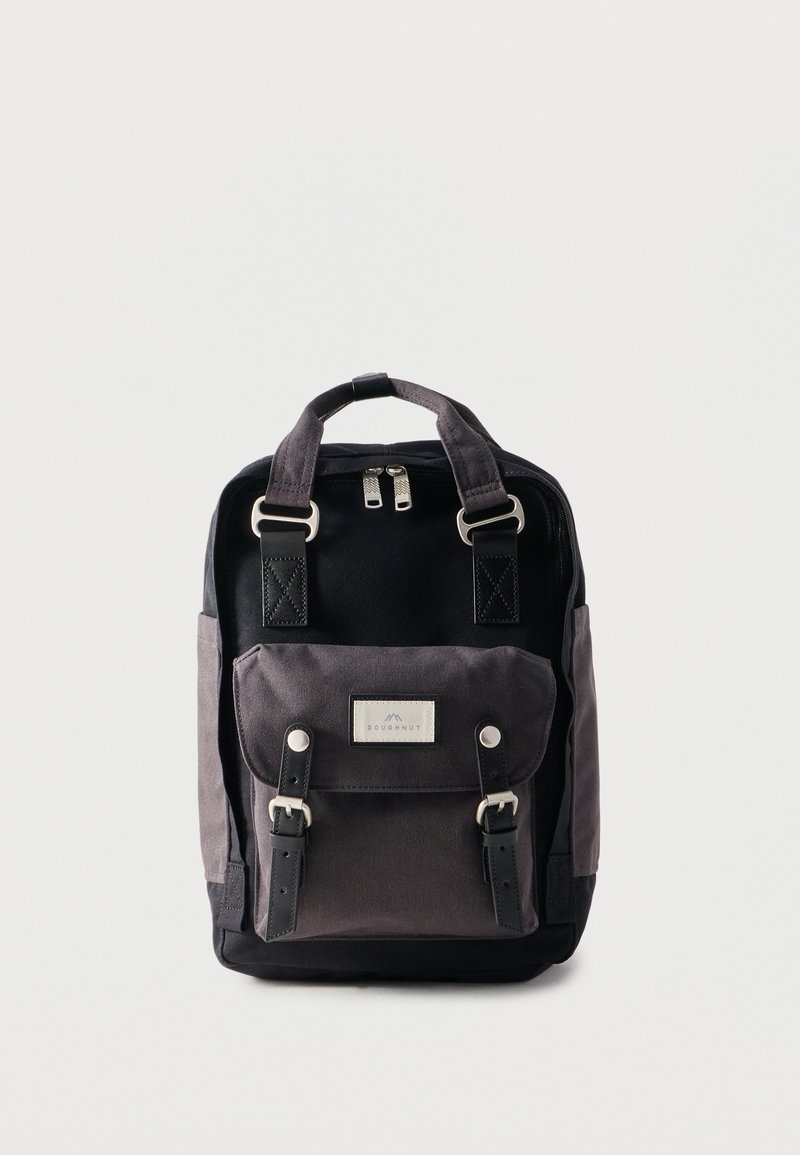 Μαύρο και γκρι σακίδιο με διπλές λαβές στο πάνω μέρος, μπροστινή τσέπη με καπάκι και ιμάντες με αγκράφες, και διπλό κλείσιμο με φερμουάρ σε απλό φόντο.