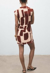 Rochie scurtă în nuanțe de crem și vișinie cu un model abstract, mâneci tip capac, siluetă ajustată, textură netedă, cu fermoar la spate și asortată cu pantofi cu toc negri.