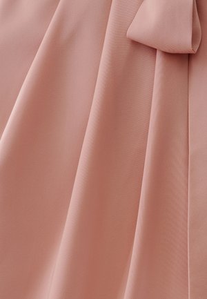 Mīksts, gaiši rozā audums ar gludu faktūru, kuram ir maigas kroku detaļas un loku akcents, piešķirot dizainam dimensiju.