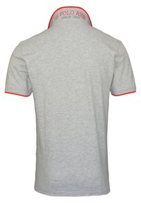 Grå pikétröja med en kontrasterande röd krage och ärmöppningar. Har texten "US POLO ASSN" broderad i nacken bak.