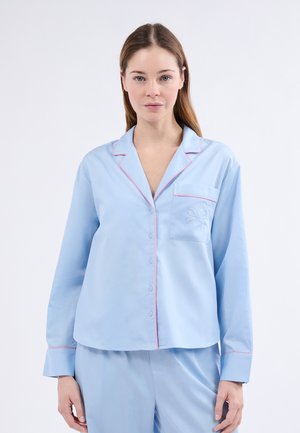 Pijama de algodón azul claro con ribete rosa, cierre de botones y un bordado decorativo de un lazo en el bolsillo del pecho. Mangas largas.