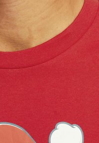 Rød bomulds T-shirt med rund halsudskæring, der har et grafisk design med en karakter og en sky, glat tekstur og korte ærmer.