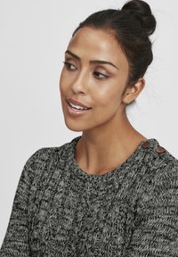 Grau strukturierter Pullover mit einem Zopfmuster, rundem Halsauschnitt und zwei braunen Knöpfen an der Schulter. Weiches Material mit einem gemütlichen Erscheinungsbild.