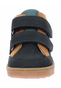 Scarpa nera e marrone con tomaia in suede, due cinturini regolabili in Velcro e suola in gomma. Design a punta arrotondata con accenti di cucitura.