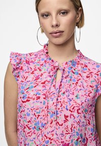 Blusa floreale rosa con maniche a volantino, scollatura a chiave e motivi astratti colorati in rosso, blu e verde. Tessuto leggero.