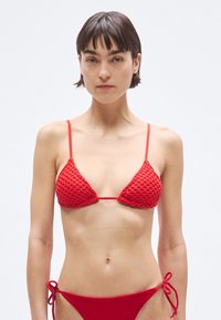 Bikini rojo de crochet con copas triangulares de diseño texturizado, tirantes finos ajustables y parte inferior de talle bajo con lazos laterales.