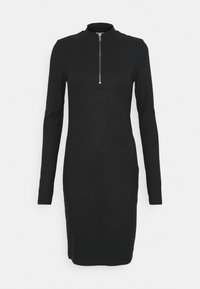 Svart ribbad klänning med hög krage och långa ärmar. Har en dragkedja fram. Slimmad passform med knälång nederkant.