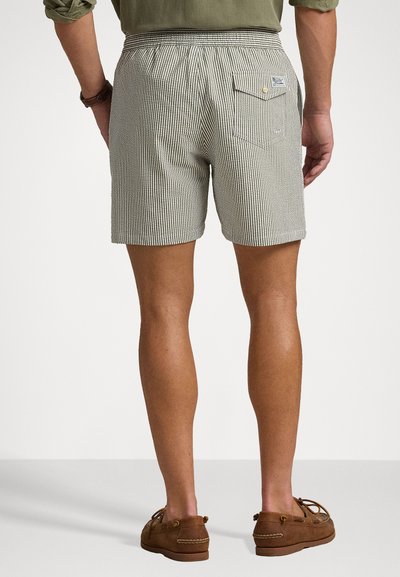 Pantaloni scurți de culoare deschisă, cu dungi, cu o talie elastică și un buzunar pe spate. Asortați cu pantofi slip-on din suede maro.