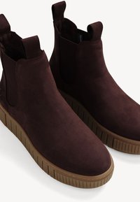 Burgundy ankle boots with elastic side panels, smooth suede texture, and a contrasting rubber sole featuring vertical ridges.