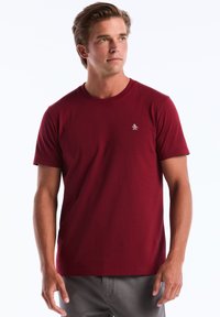 Bordeaux crew neck T-shirt van katoen, met een klein pinguïnlogo op de linkerkant van de borst en korte mouwen. Effen kleur met een soepele textuur.