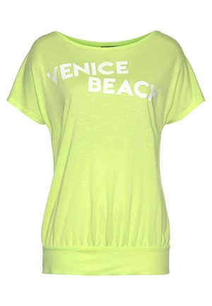 Jasnożółta luźna koszulka z krótkim rękawem z nadrukiem "VENICE BEACH" białym kolorem na piersi.