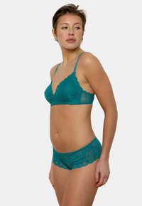 Ensemble bralette en dentelle et short en teal, avec des bords festonnés et des motifs floraux délicats, fabriqué en tissu doux et léger.