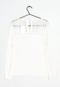 Blusa bianca a maniche lunghe con corpo testurizzato, scollo in pizzo trasparente e apertura a chiave sul retro con chiusura a bottone. Tessuto liscio con motivo a coste.