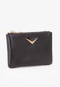 Portafoglio in pelle nera con una texture liscia, caratterizzato da un accento triangolare in tonalità oro sulla parte anteriore, chiusura con zip e una forma rettangolare compatta.