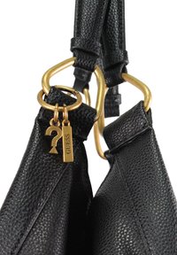 Schwarze Handtasche aus genarbtem Leder mit goldfarbenen Beschlägen, doppelten Griffen und Schlüsselanhängern mit Fragezeichen und "GUESS"-Etikett.