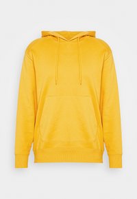 Sudadera amarilla con capucha, bolsillo frontal y cordón, sobre un fondo blanco liso.