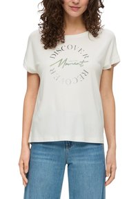 Kurzärmliges, cremefarbenes T-Shirt aus weichem Stoff mit einem kreisförmigen Grafikdesign und dem Text "Entdecke den Augenblick" in unterschiedlichen Texturen.