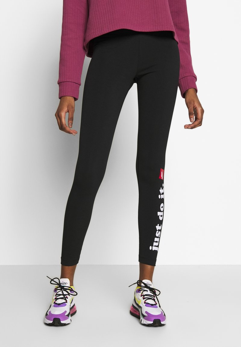 Svarta leggings med en åtsittande design, prydda med en vit "just do it"-grafik på sidan. Bärs med en lila ribbad tröja och färgglada sneakers.