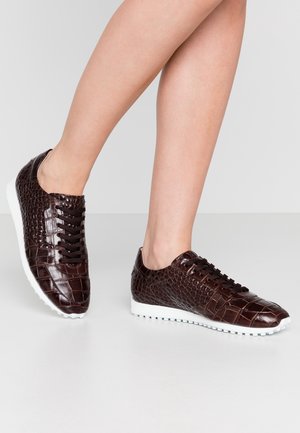 Baskets en cuir synthétique crocodile marron avec un motif texturé, semelles en caoutchouc blanches et lacets noirs. Design bas avec une pointe arrondie.