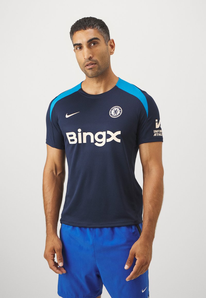 Koszulka Nike Chelsea FC w kolorze granatowym z niebieskimi akcentami na ramionach, z logo "Bingx" w jasnej kremowej barwie oraz krótkimi rękawami, co zapewnia dopasowany krój.