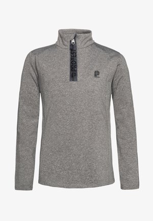Dreng står iført en grå kvart-zip pullover, grønne vandtætte bukser og sorte støvler mod en ensartet lys baggrund.