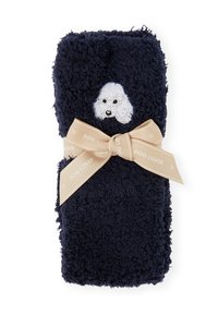 Coperta soffice blu navy con una texture peluche, con un volto di cane bianco ricamato, legata con un nastro crema con l'etichetta "AMANTE DEI CANI".