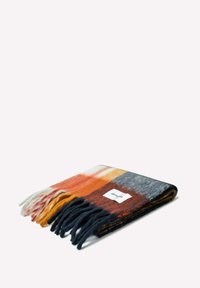 Couverture en laine avec des bords frangés, présentant des rayures horizontales en orange, gris, marine et crème. Étiquette visible sur le pli.