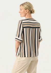 Stribet bluse med sorte, cremefarvede og orange lodrette striber, korte ærmer og en afslappet pasform med rygdetalje.