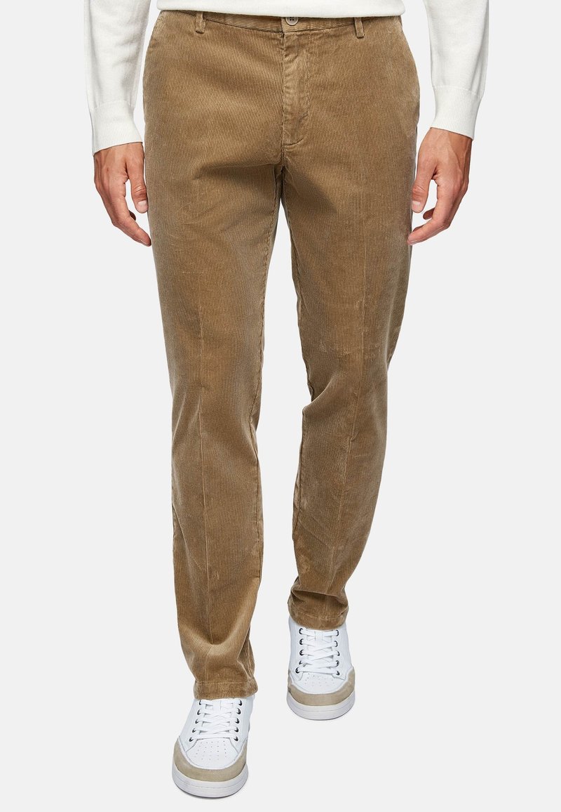 Brown corduroy pants with vertical ribbed texture, featuring a straight fit and side pockets, paired with white sneakers.