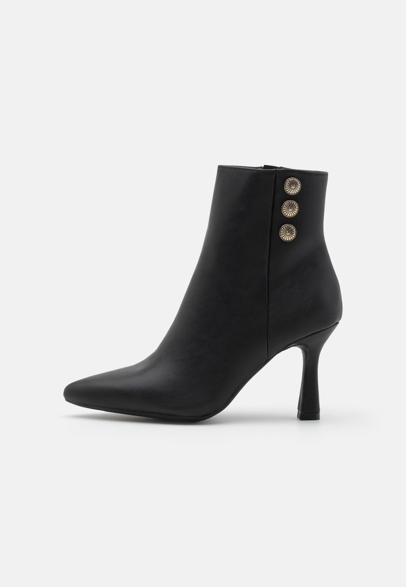 Bottine en cuir noir avec un bout pointu, un talon haut slim, et trois boutons décoratifs dorés sur le côté extérieur.