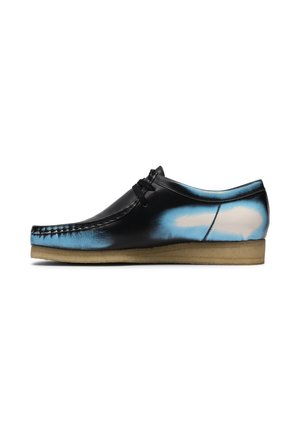 Scarpa stringata in pelle nera con accenti sfumati blu e bianchi e suola beige in crepe, mostrata di profilo su sfondo bianco.