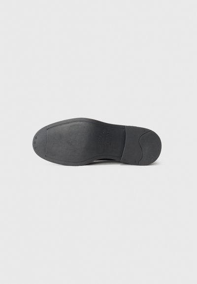 Black rubber shoe sole with a smooth texture, rounded shape, and logo detail. Features minimal tread pattern for grip.