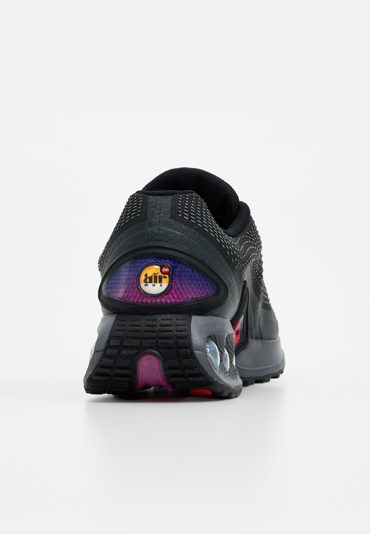 Chaussure de sport noire et grise vue de l'arrière, présentant un coussin Air Max visible et un accent violet, rouge et jaune sur la semelle.