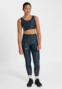 Sportowy krótki top i legginsy z wysokim stanem w ciemnoniebieskim kolorze z falistym wzorem. Wykonane z elastycznego materiału z akcentami logo i teksturowanym wykończeniem.