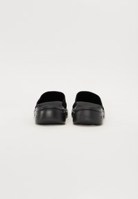 Sorte slip-on sko med en glatt skinnoverflate og myk stofffôr, med en avrundet tå og et lavprofildesign.
