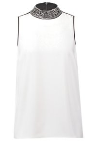 Top blanc sans manches avec un col montant noir orné de plusieurs rangées de décorations argentées et une fermeture éclair au dos.