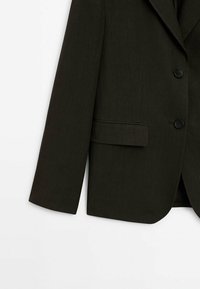 Manche et moitié inférieure d'un blazer marron foncé ajusté, avec deux boutons et une poche à rabat, sur fond blanc.