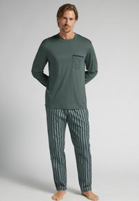 Zelená košile s dlouhým rukávem a náprsní kapsou, spárovaná s modro-bíle pruhovanými kalhotami, obojí vyrobené z hladké tkaniny. Měkká textura, rovný střih.