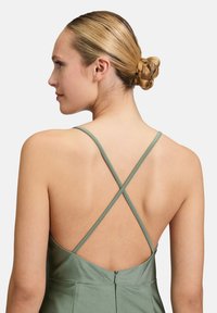 Grünes Satin-Kleid mit kreuzgeknüpften Spaghetti-Trägern, offener Rückseite und verdecktem Reißverschluss, das eine glatte Textur und elegantes Design präsentiert.