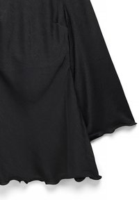 Mustast kangast ülaosa, millel on tekstuuriga pind, laiad varrukad ja laineline ääreosa. Omaduseks on lahtine istuvus ning puuduvad nähtavad kinnitused või aksessuaarid.