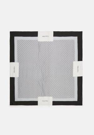 Vierkante zwarte en grijze sjaal met een herhaald "CK"-patroon en witte rechthoekige stukken met de tekst "Calvin Klein" aan alle vier de zijden.