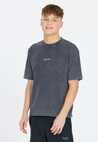 Harmaa crewneck-t-paita, jossa on lyhyet hihat ja kulunut pinta. Edessä on valkoinen teksti "LES'ARCS". Rennon mallinen.