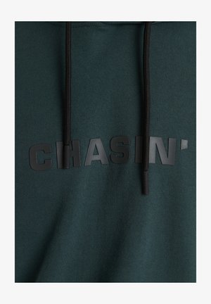 Zelená bavlněná mikina s kapucí s texturovaným černým gumovým logem "CHASIN'" na hrudi, černými tkaničkami a hladkým povrchem.