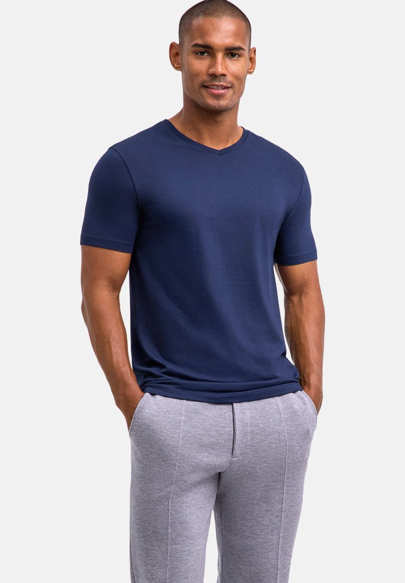 Granatowy T-shirt z krótkim rękawem i dekoltem w kształcie litery V, wykonany z miękkiego materiału, zestawiony z jasnoszarymi, zwężającymi się dresami z bocznymi szwami.