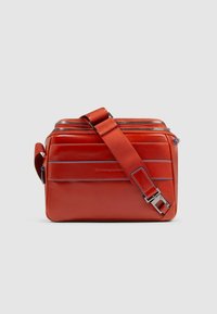 Bolso mensajero de cuero rojo con herrajes plateados, dos compartimentos con cremallera, correa ajustable y costuras de acento en azul.