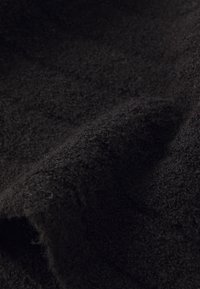 Tessuto nero con una superficie morbida e pelosa, caratterizzato da una piega leggermente ondulata che mette in evidenza la sua spessore e morbidezza.